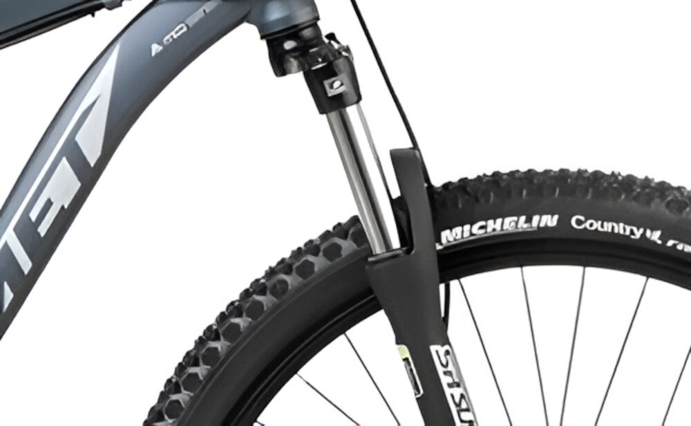 Rower górski MTB ROMET Rambler Fit U18 27.5 cala Czarno-srebrno-niebieski zbliżenie na amortyzator rower typu hardtail przedni amortyzator marki SUNTOUR typ XCE długość skoku 100 mm ułatwia najeżdżanie na przeszkody niweluje wstrząsy niska masa roweru duża sztywność regulacja za pomocą sprężyny obsługa poprzez manetkę