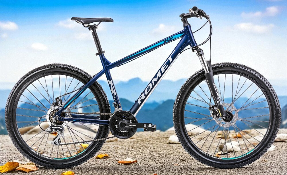 Rower górski MTB ROMET Rambler R7.1 V2 U19 27.5 cala Granatowy rower na tle gór nieba środek codziennego transportu relaks pasja uniwersalność