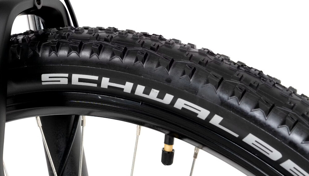 Zbliżenie na czarną oponę rowerową z widocznym bieżnikiem i napisem \'SCHWALBE\'.