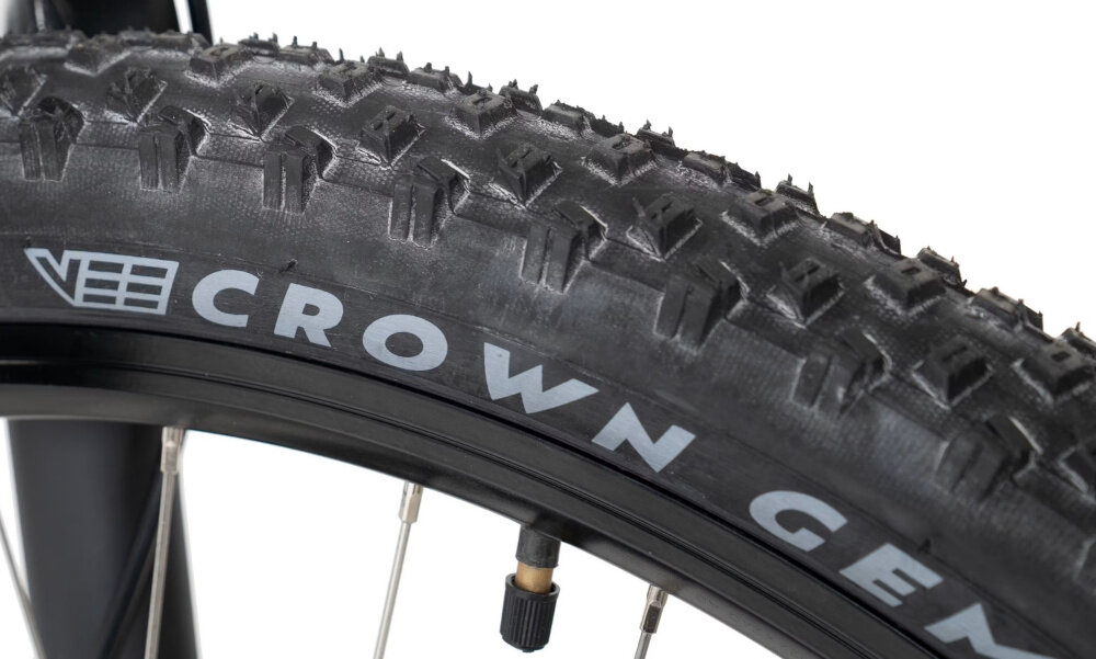 Zbliżenie na oponę rowerową z widocznym bieżnikiem i napisem \'CROWN GEM\'.