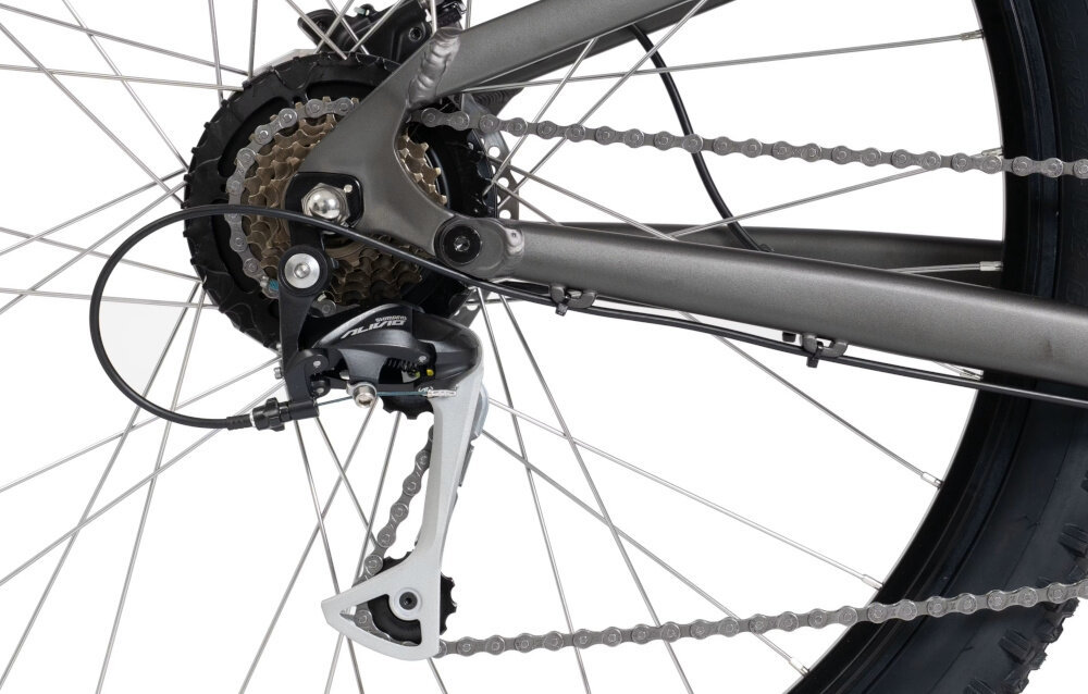 Zdjęcie przedstawia tylną część roweru z widocznym mechanizmem przerzutki i łańcuchem. Rower ma grafitowy kolor ramy i czarne opony.