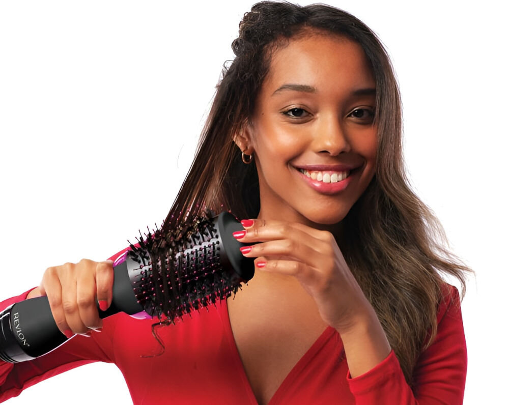 Osoba używa suszarko-lokówki z widocznym logo \'REVLON\'. Urządzenie ma czarny kolor i okrągłą szczotkę z włosiem.