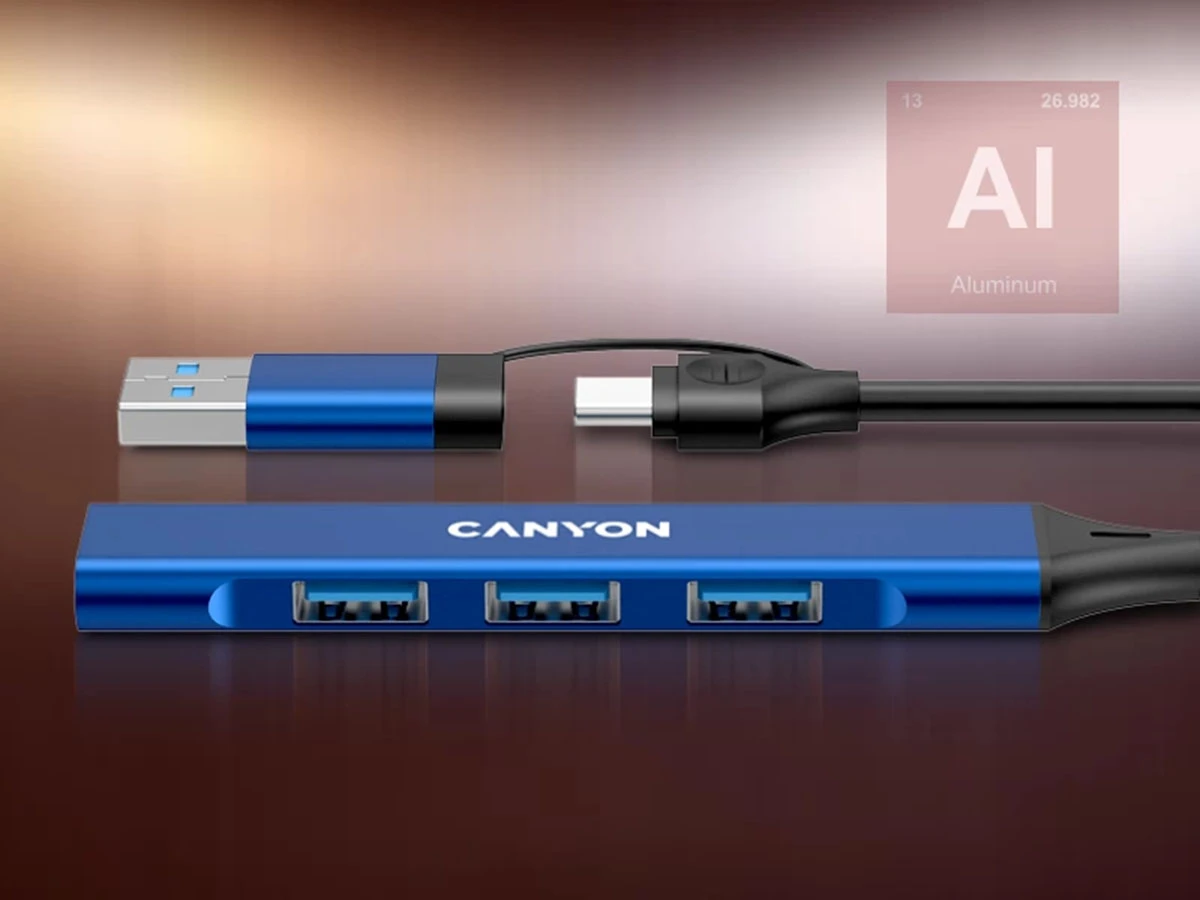 Na obrazie widoczny jest niebieski hub USB z trzema portami, oznaczony logo CANYON. W tle znajduje się symbol AI z napisem \'Aluminum\'.