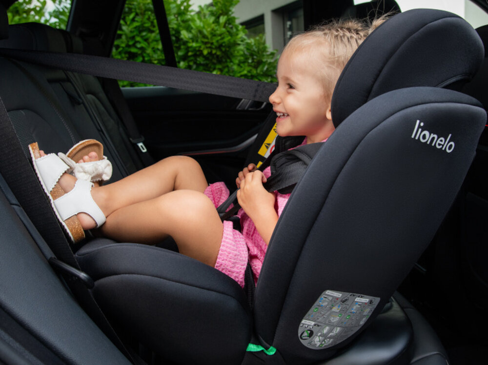 Fotelik samochodowy LIONELO Bastiaan i-Size 40-150 cm (0-36 kg) Niebieski wnętrze samochodu dziecko siedzi w foteliku tyłem do kierunku jazdy uśmiecha się w tle dom drzewa  montaż tyłem (RWF) i przodem (FWF) dostosowanie jazdy do wieku i etapu rozwoju dziecka montaż RWF rekomendowany dla najmłodszych możliwość przejścia na FWF ułatwia przewożenie starszych dzieci