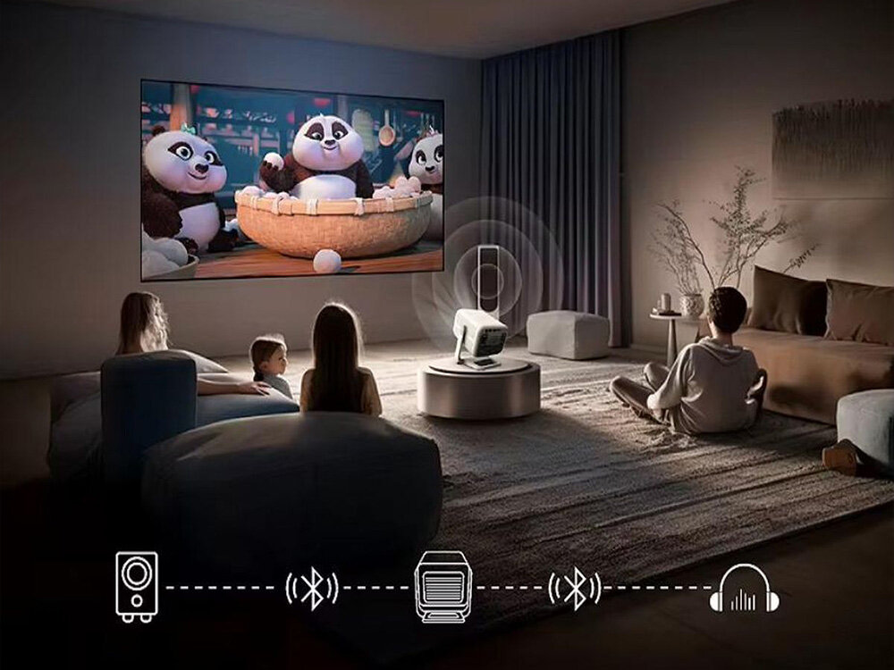Projektor ZENWIRE H8 głośnik 5W Bluetooth 5.0 mini Jack, osoby siedzące w pokoju, porjketor stojący na stoliku wyświetlający obraz