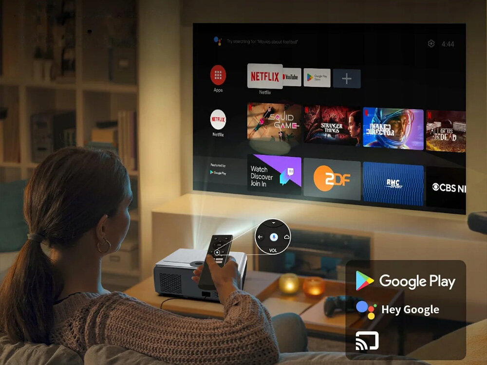 Projektor Zenwire E690H Chromecast przesyłanie obrazu telefon laptop, osoba siedząca na kanapie z pilotem w ręku, projektor wyświetlający obraz na ścianie
