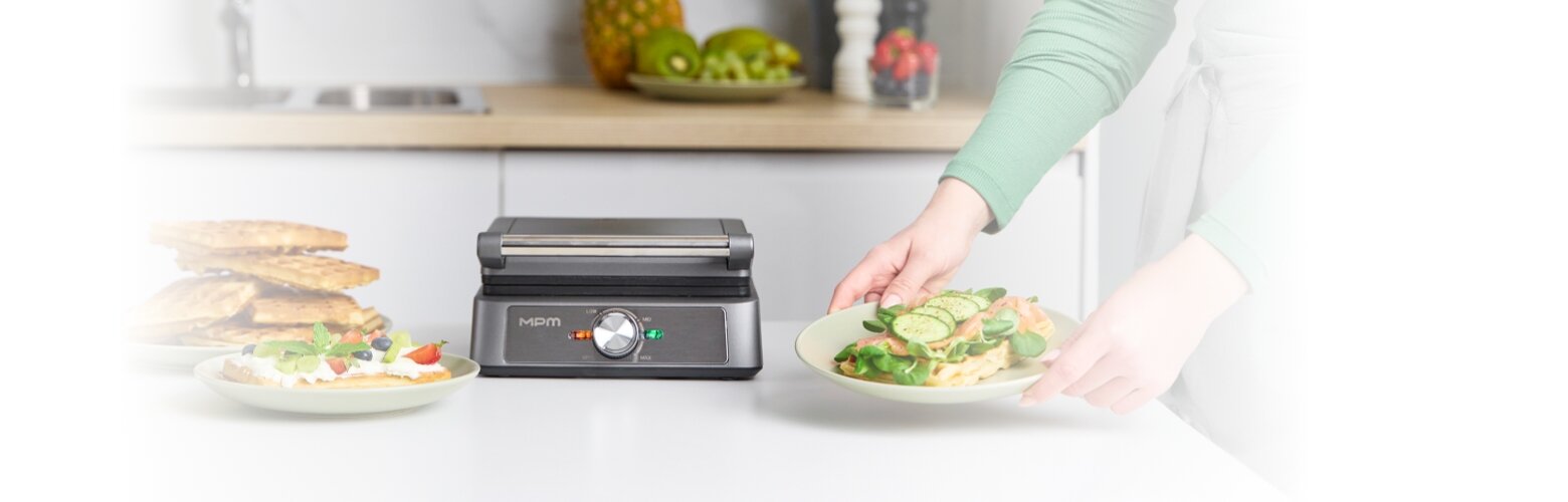 Gofrownica MGO-55 na kuchennym blacie w otoczeniu gofrów - na słodko i wytrawnych - na talerzu.