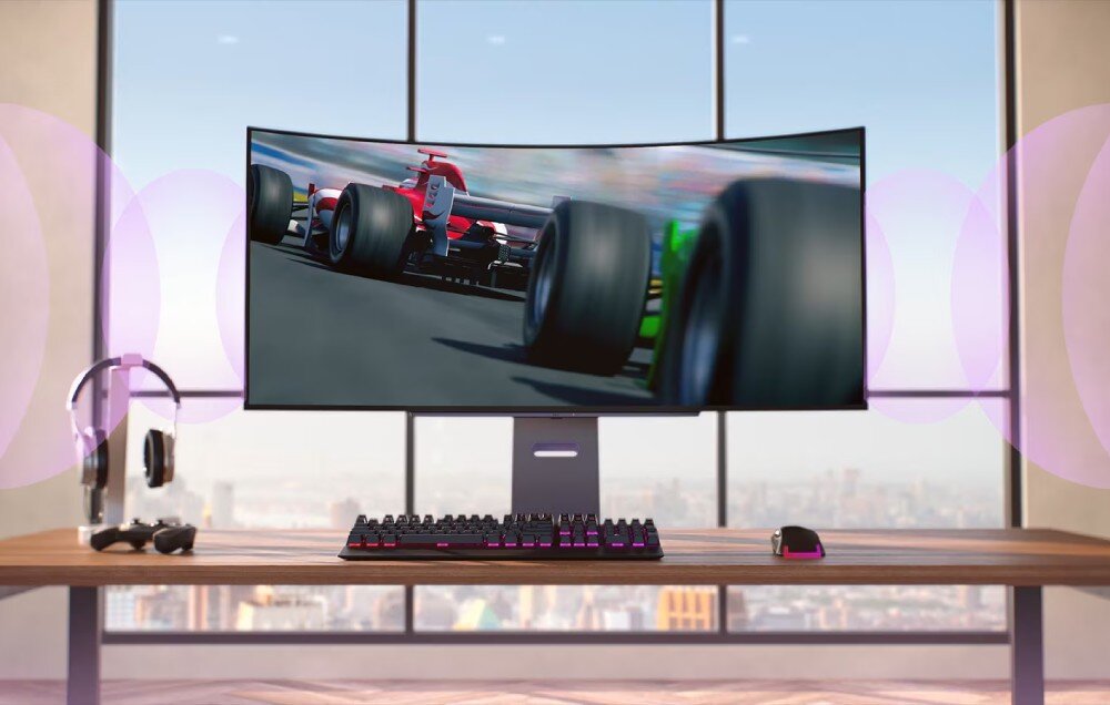 Monitor LG UltraGear 45GX90SA-B.AEU Monitor wyświetlający wyścig Formuły 1 na tle dużych okien, po bokach widoczne fale dźwięku sugerujące efekty audio, na biurku klawiatura, myszka i słuchawki, głośniki, dźwięk, moc