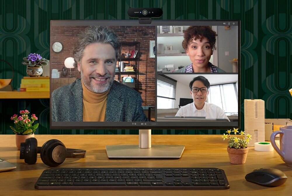 LOGITECH Brio RightLight 3 wysoki zakres dynamiczny HDR Logitech BRIO 4K optymalizuje sposób prezentowania twarzy - Widok na całe stanowisko biurowe podczas wideokonferencji z wieloma uczestnikami wyświetlanymi na monitorze