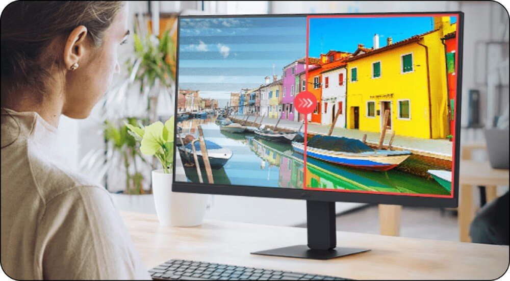 Monitor LG 24U631A-B Kobieta siedząca przy biurku, patrzy na ekran monitora. Połowa ekranu przedstawia wyblakły obraz miasta nad wodą, a druga połowa żywe, nasycone kolory tej samej sceny, ochrona wzroku, migotanie