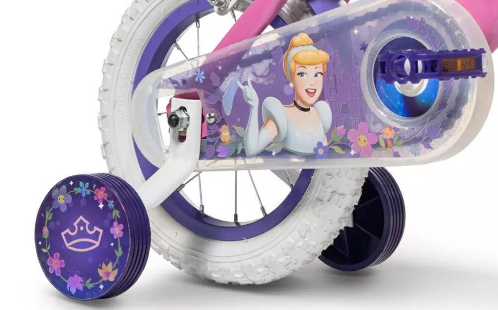 Rower dziecięcy HUFFY Disney Princess 12 cali Różowy Wzrost: 85-100 cm Wiek: 3-5 lat zbliżenie na kółka boczne i osłonę łańcucha zdjęcie na białym tle boczne kółka asekurują dziecko w początkowej fazie nauki boczne kółka można łatwo usunąć osłona łańcucha kolorowa grafika zabezpiecza łańcuch przed brudem