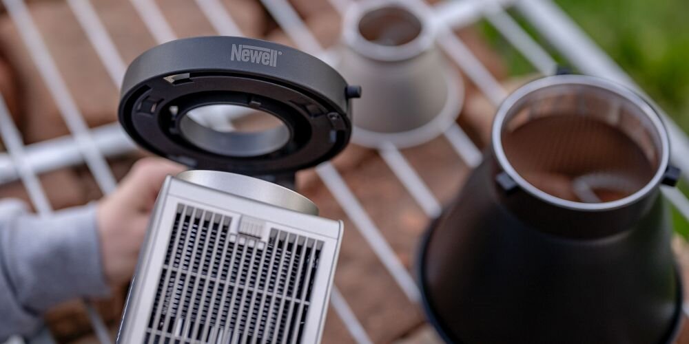 Widok z góry na srebrną lampę Newell, czarny pierścień adaptera oraz dwa klosze leżące na metalowej kratce.