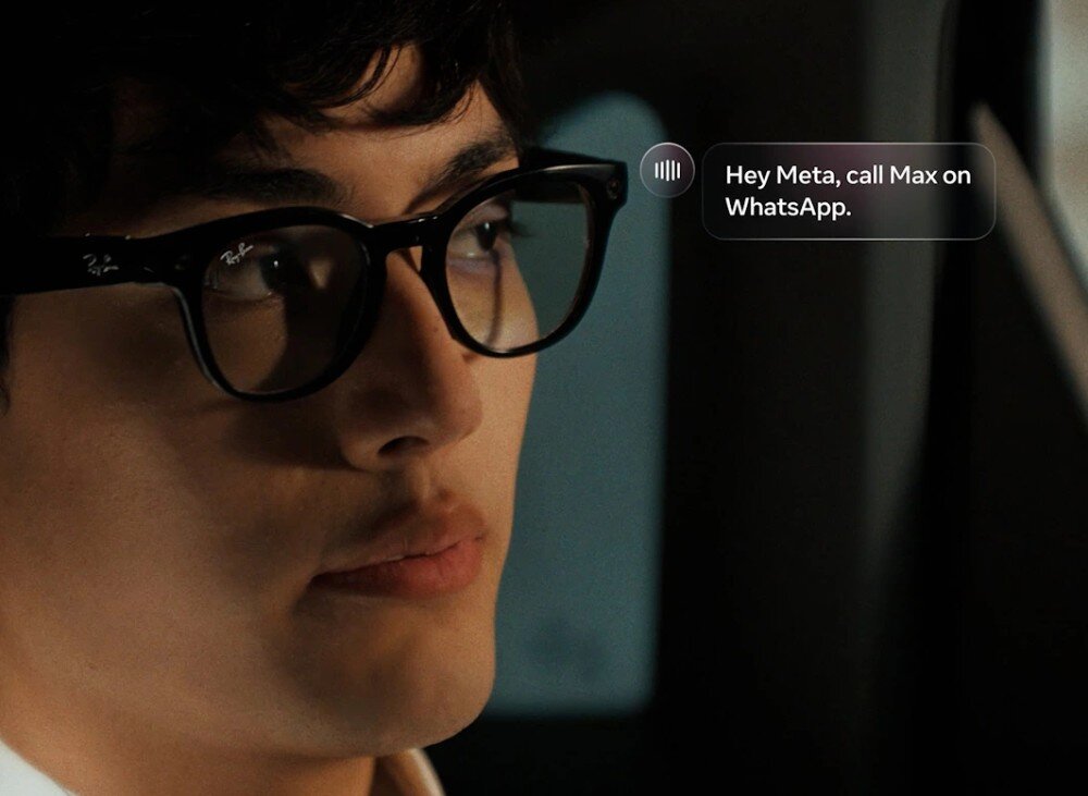 Okulary META Ray-Ban Wayfarer zbliżenie na twarz mężczyzny w czarnych okularach korekcyjnych z widocznym obiektywem aparatu w rogu oprawki, obok głowy unosi się graficzny dymek z napisem 'Hey Meta, call Max on WhatsApp'