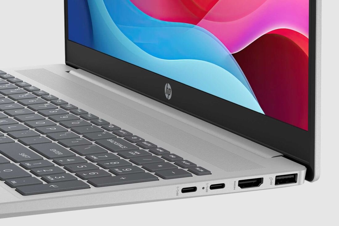 Laptop HP Pavilion 16 w srebrnej obudowie z ekranem prezentującym kolorowe, abstrakcyjne fale w odcieniach niebieskiego, różowego i czerwonego, widok z góry na klawiaturę i porty boczne, na jasnym tle. - Ekologia w każdej części