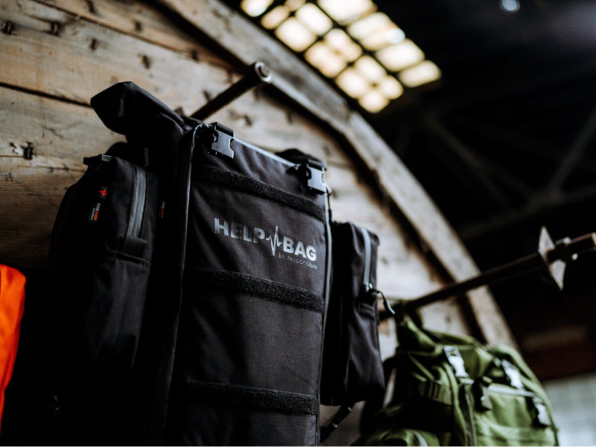 Plecak ewakuacyjny HELP BAG Max Czarny, moduły, akcesoria, rozmieszczenie, kolory, w tle środek opuszczonej fabryki, plecak helpbag zawieszony na kołkach ścian