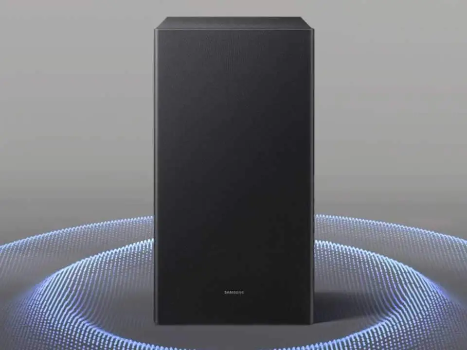 Czarny subwoofer z logo \'SAMSUNG\' na dole, otoczony niebieskimi, świetlnymi falami na szarym tle.