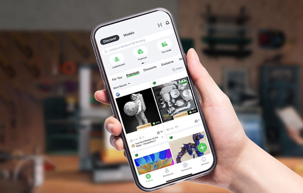 Drukarka 3D CREALITY Hi Wi-Fi prezentacja włączonej aplikacji na telefonie trzymanym w ręce w tle warsztat Creality OS tryb eksperta zarządzanie filamentami integracja FLUIDD WebUI Creality Print 40 predefiniowanych ustawień obsługa 3MF Creality Cloud zdalne sterowanie dostęp do biblioteki modeli interakcja użytkowników