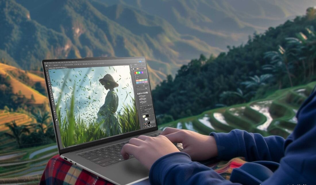 Osoba pracująca na laptopie Lenovo Yoga Slim 7 w górach, na ekranie edytor graficzny z portretem kobiety w polu, nowoczesny ultrabook do kreatywnej pracy mobilnej, widok na tarasy ryżowe w tle