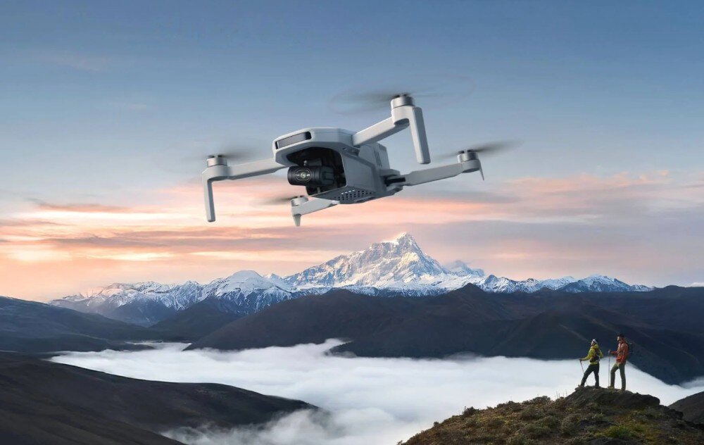 Dron POTENSIC Atom 2 Standard Kit Szary dron lecący na tle ośnieżonych szczytów górskich i zamglonej doliny