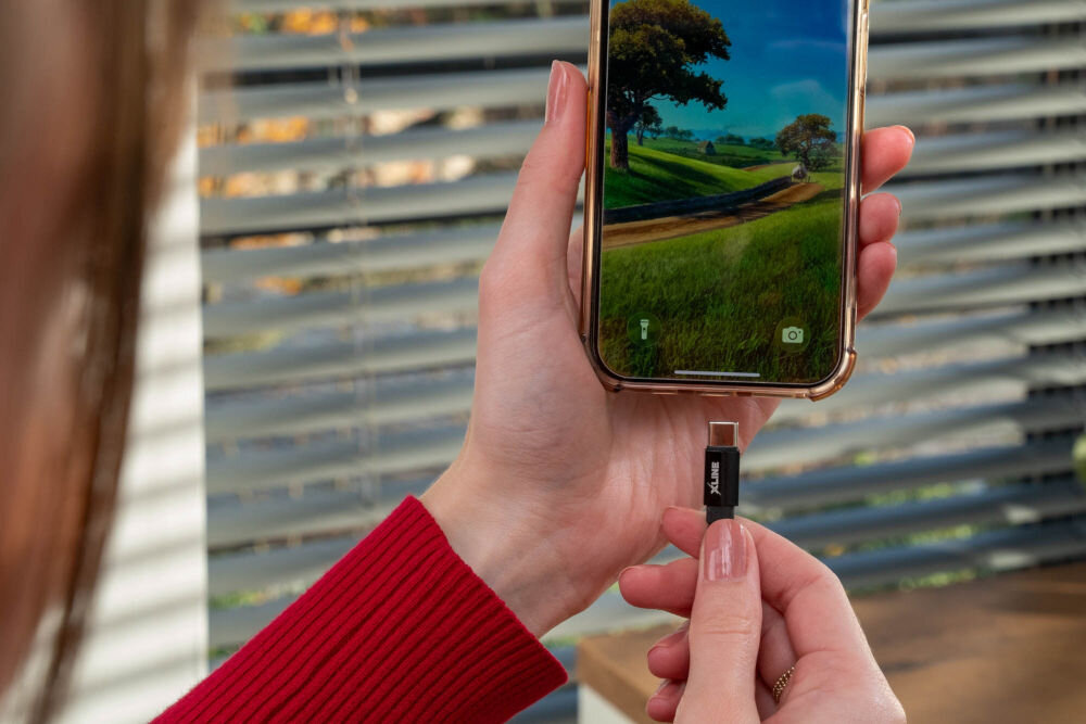 Kabel XLINE UC02KFC-AC USB-A do USB-C do telefonu laptopa ładowarka szybkie ładowanie 60W Dłoń trzymająca smartfon i wpinająca wtyk USB-C kabla XLINE, ilustrująca codzienne ładowanie telefonu za pomocą szybkiego przewodu z nylonową izolacją.