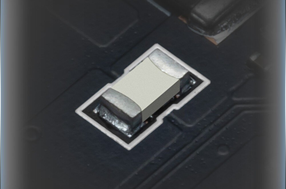 Karta graficzna MSI GeForce RTX 5060 Ventus 2X OC 8GB Zbliżenie na pojedynczy bezpiecznik na płytce drukowanej, osadzony między innymi elementami elektronicznymi, zabezpieczenia, bezpieczniki