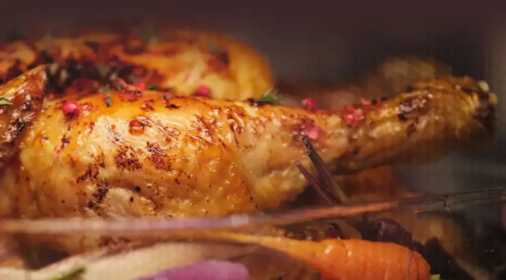 Ręka wyciągająca blachę z upieczonymi pomidorkami