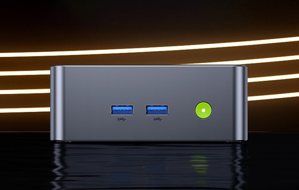 Komputer GMKTEC NucBox M3 Plus Widok na front małego komputera w czarnej obudowie z dwoma portami USB i zielonym przyciskiem zasilania, gniazda, złącza, podłączenie