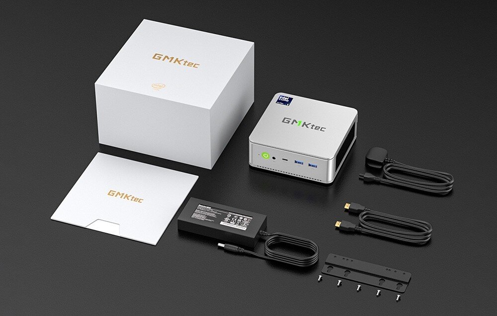 Komputer GMKTEC NucBox K9 Zestaw akcesoriów na czarnym tle: srebrny mini komputer, biały karton z logiem producenta, zasilacz, dwa przewody, uchwyt montażowy z śrubami