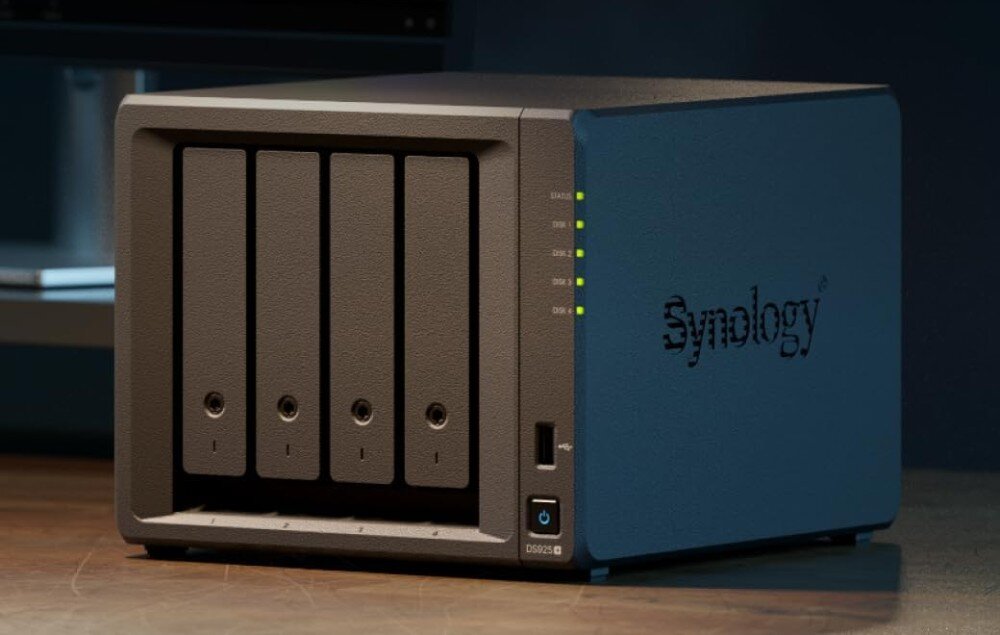 Serwer plików SYNOLOGY DS925+ Urządzenie z czterema pionowymi zatokami na dyski twarde, podświetlonymi diodami LED, stojące na biurku z logo 'Synology' z boku obudowy, opis