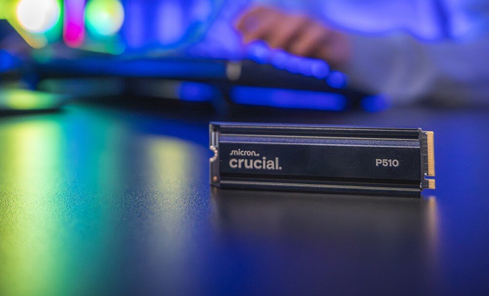 Dysk CRUCIAL P510 Zbliżenie na dysk z logo 'crucial P510' ustawiony na czarnej powierzchni, w tle rozmyte światła RGB i dłoń przy klawiaturze, opis