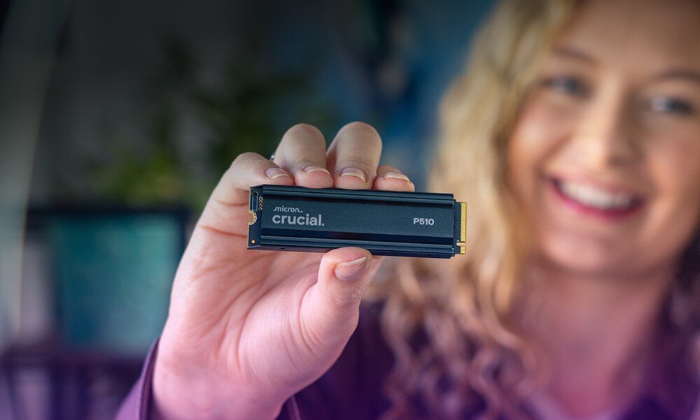 Dysk CRUCIAL P510 Kobieta z blond lokami trzyma w palcach dysk 'crucial P510' i uśmiecha się, patrząc przed siebie, jakość, żywotność