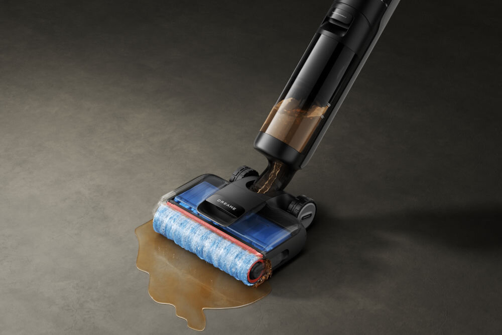 Odkurzacz z niebieskim wałkiem czyszczącym zbiera rozlany płyn z podłogi. Na urządzeniu widoczne jest logo \'DREAME\'.