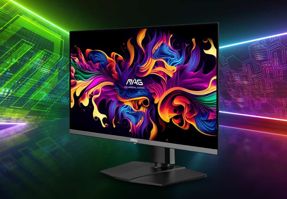 Monitor MSI MAG 272QP Monitor z kolorowym, abstrakcyjnym wzorem na ekranie, stojący na czarnym biurku, w tle zielone i fioletowe geometryczne światła