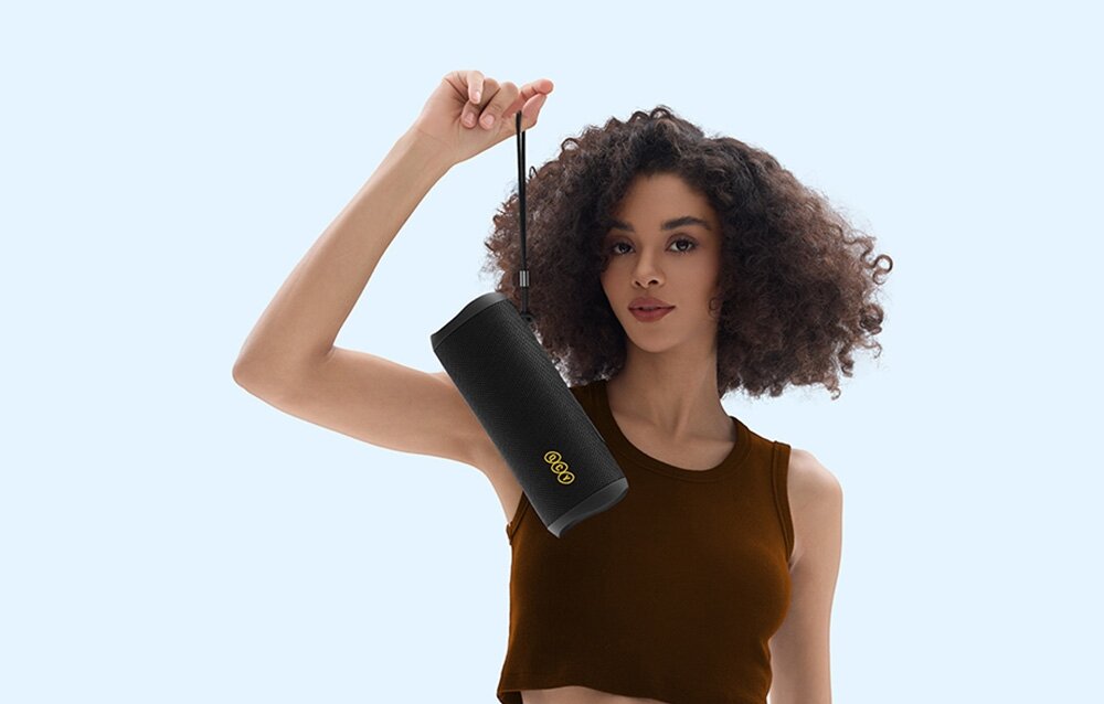 Głośnik mobilny QCY SP7 tryb basowy wzmocnienie niskich tonów imprezy, osoba trzymająca głośnik za pasek