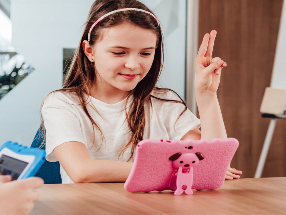 Tablet BLOW Kids Tab 7 V2 7 cali 4/32 GB Wi-Fi Różowy prezentacja urządzenia dziewczynka patrząca w tablet i zgłaszająca się na zajęciach bateria 3000 mAh wiele godzin bez częstego ładowania podróże wyjazdy niewielki rozmiar 196,7 x 130 x 11,8 mm lekka konstrukcja 390 g 7-calowy ekran IPS rozdzielczość 1280 x 800 px szerokie kąty widzenia ostrość obrazu