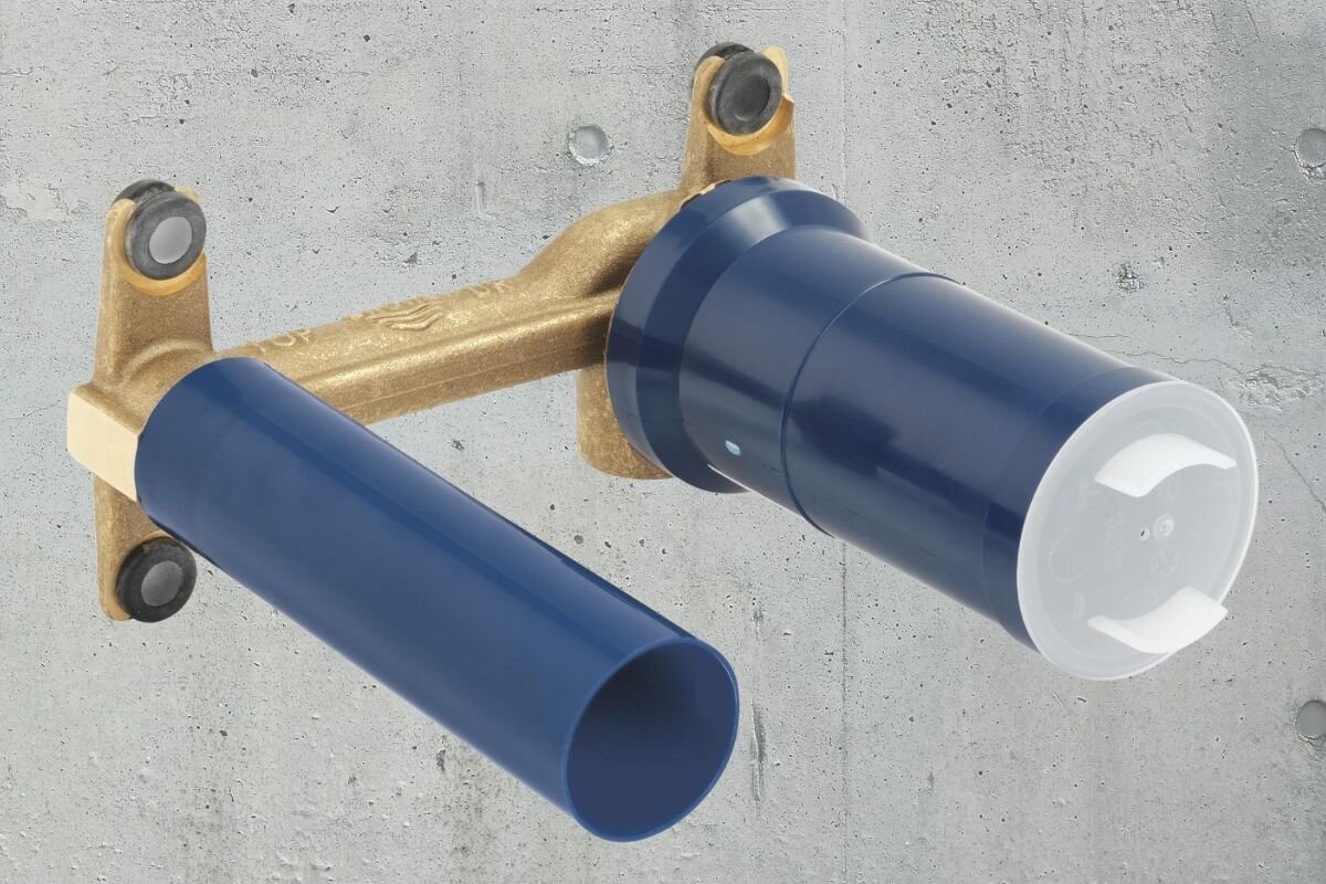 ELEMENT PODTYNKOWY BATERII 2-OTWOROWEJ GROHE 23571000 Podtynkowy element instalacyjny z mosiężnym korpusem i niebieskimi osłonami pokazany na tle betonowej ściany