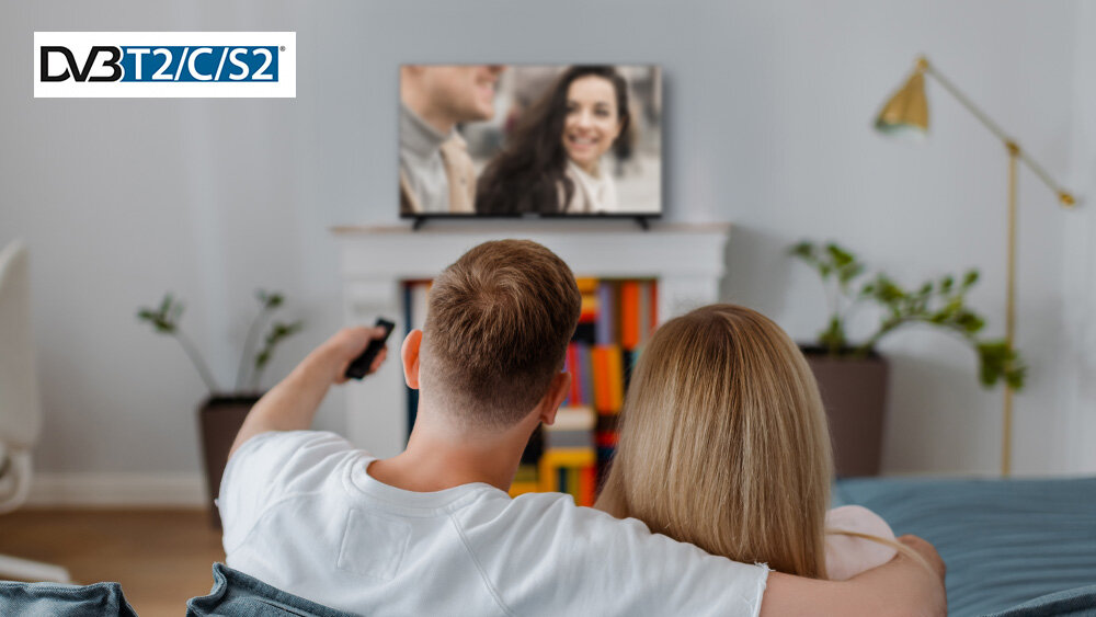 Telewizor TELEFUNKEN TFL-40BPF1000 - Wbudowany tuner DVB-T2/C/S2, HEVC H.265, telewizor stojący na postumencie kominka, osoby siedzące na kanapie