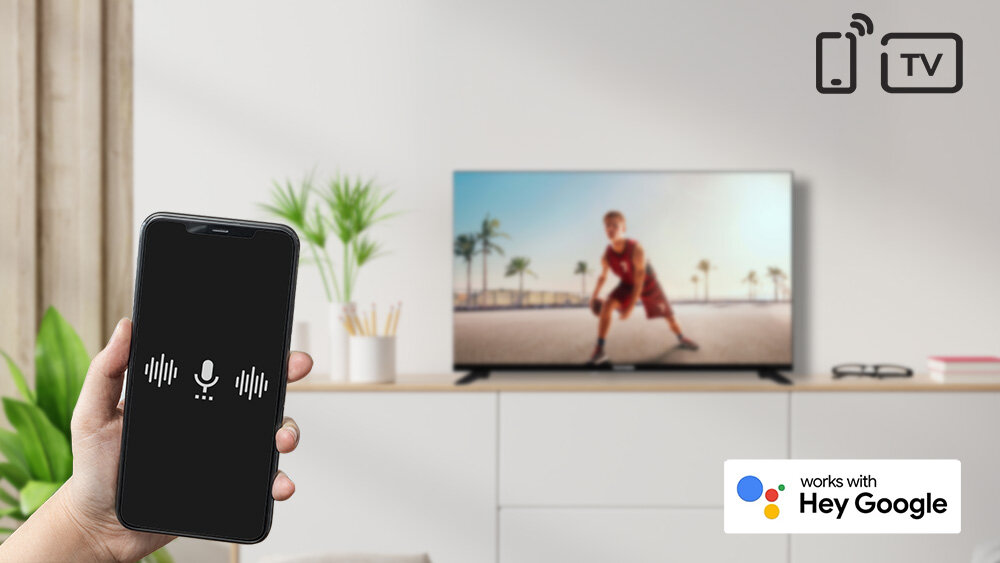 Telewizor TELEFUNKEN TFL-40APF1000 - Wydawaj komendy głosowe, Asystent Google, telewizor stojący na komodzie, ręka trzymająca smartfona