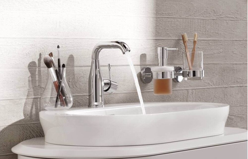 BATERIA UMYWALKOWA STOJĄCA GROHE ESSENCE STARLIGHT CHROME 23463001 Chromowana bateria umywalkowa zamontowana przy owalnej umywalce, z wodą płynącą z wylewki w eleganckiej aranżacji łazienkowej