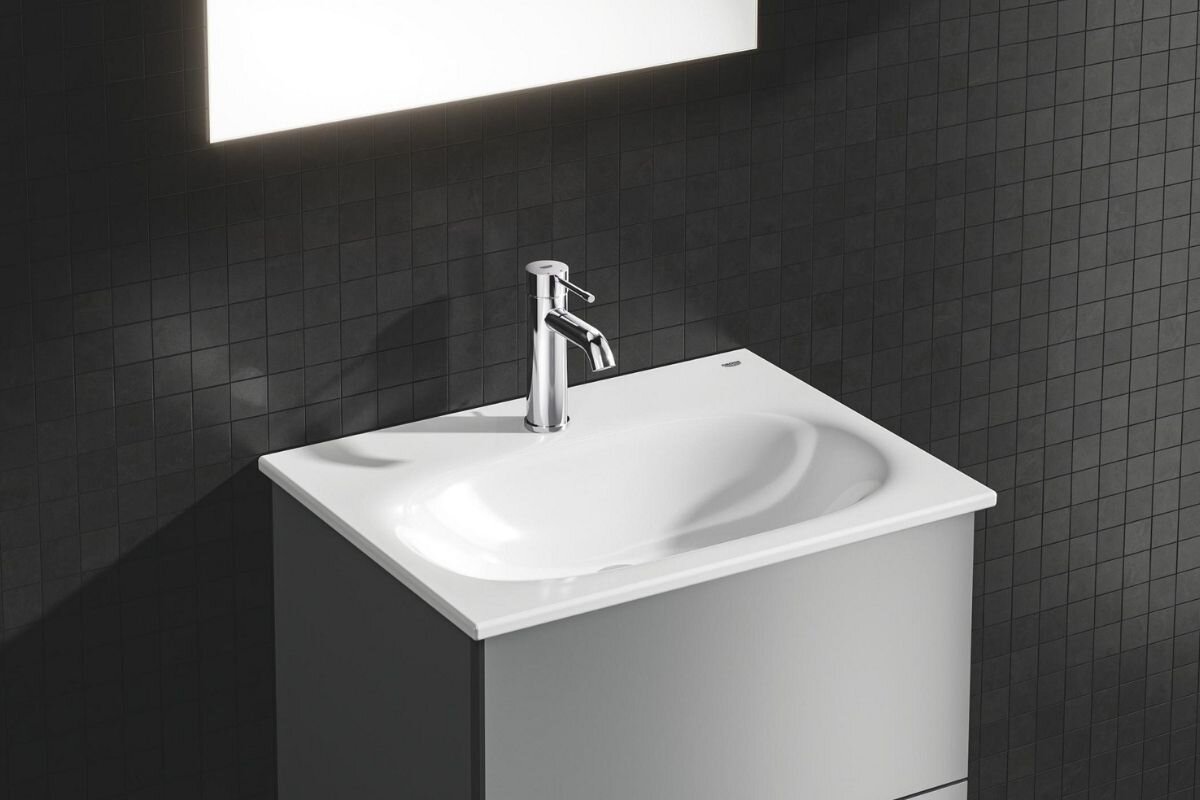 BATERIA UMYWALKOWA STOJĄCA GROHE ESSENCE STARLIGHT CHROME 23589001 Chromowana bateria umywalkowa zamontowana przy owalnej umywalce, z wodą płynącą z wylewki w eleganckiej aranżacji łazienkowej