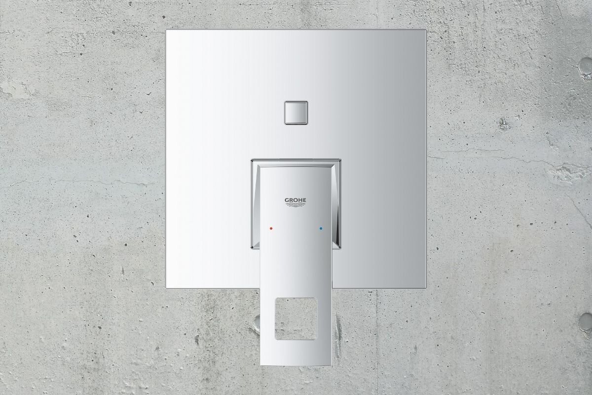 BATERIA WANNOWO-PRYSZNICOWA GROHE EUROCUBE PODTYNKOWA 24062000 CHROM Na zdjęciu widoczny jest element armatury łazienkowej zamontowany na ścianie wykończonej betonową okładziną. Całość utrzymana jest w minimalistycznym, eleganckim stylu