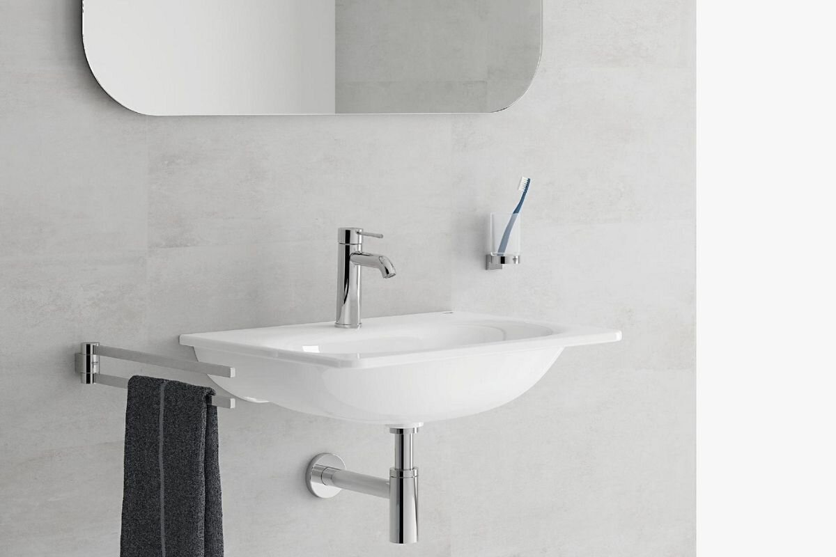 BATERIA UMYWALKOWA GROHE ESSENCE STOJĄCA 23590001 CHROM Zdjęcie ukazuje ścienną aranżację łazienki z prostokątną umywalką i chromowaną baterią stojącą zamontowaną na jej krawędzi. Obok widać uchwyt na ręcznik oraz wieszak ze szczoteczką, tworzące spójny, minimalistyczny zestaw