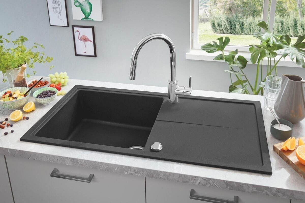 BATERIA KUCHENNA GROHE CONCETTO 31483002 CHROM Chromowana bateria kuchenna zamontowana przy dużym czarnym zlewie w jasnej kuchni elegancka smukła wylewka cylindryczny korpus uchwyt chrom kuchnia kompatybilna zlewozmywaki