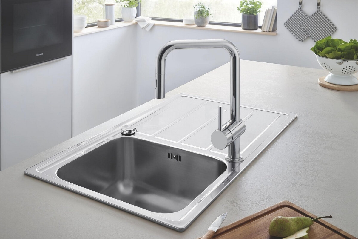 BATERIA KUCHENNA GROHE MINTA 32322002 CHROM Stalowy zlew z ociekaczem i chromowaną baterią zamontowany w jasnej kuchni z dużymi oknami