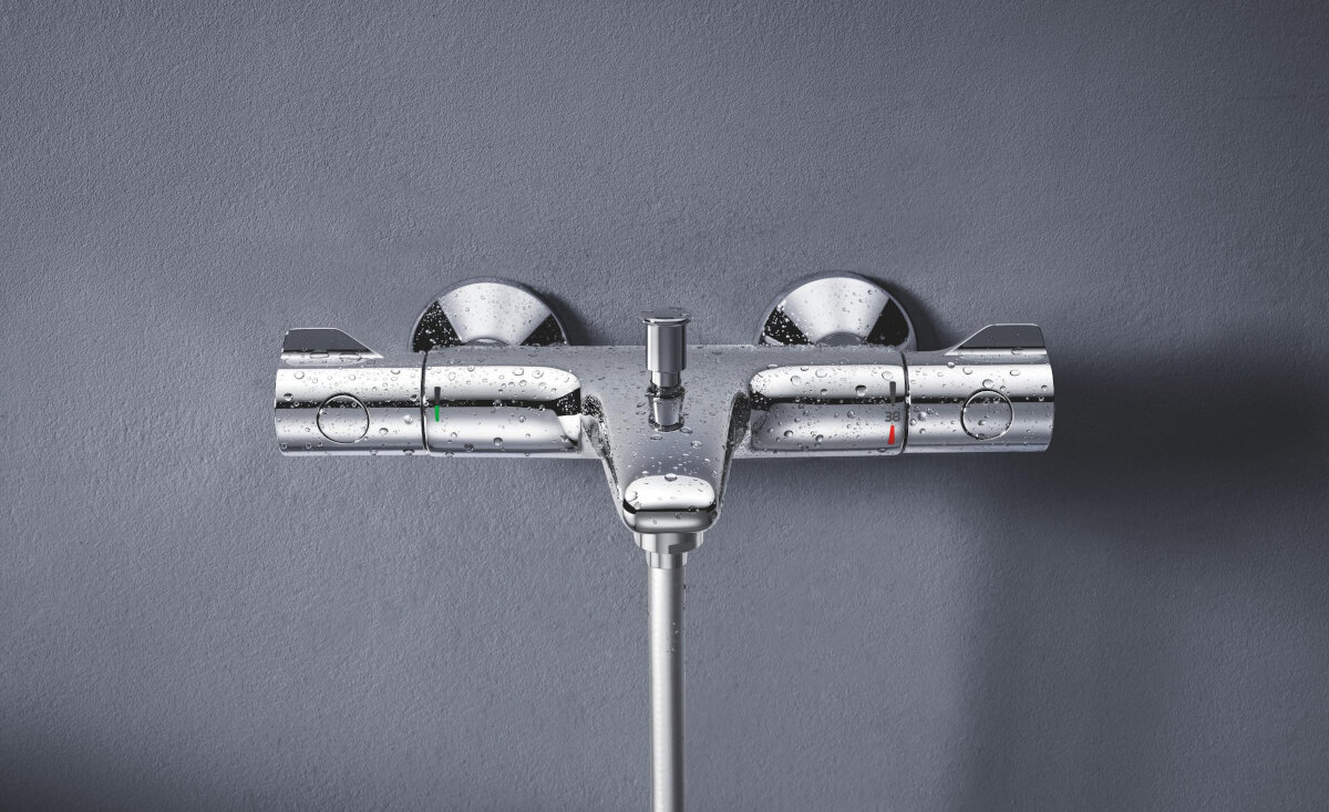 BATERIA WANNOWO-PRYSZNICOWA GROHE GROHTHERM 800 ŚCIENNA 34567000 Bateria termostatyczna zamontowana na ścianie, pokryta kroplami wody w realistycznej aranżacji łazienkowej