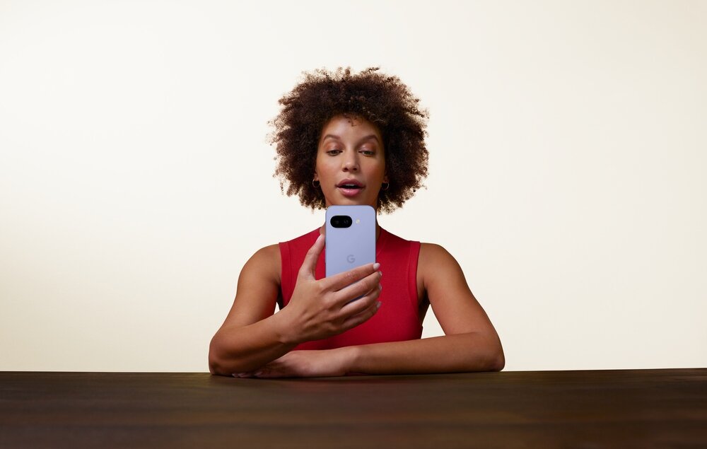 Smartfon GOOGLE Pixel 9a trzymany przez kobietę siedzącą przy stole  