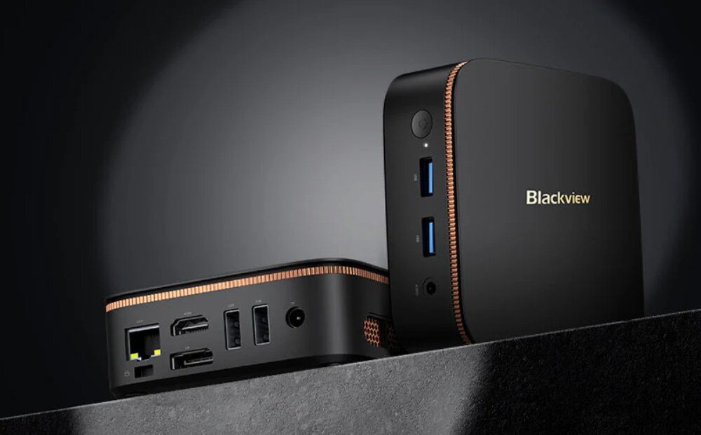 Komputer BLACKVIEW MP20 Dwa małe czarne urządzenia z miedzianą krawędzią stoją na ciemnym tle, jedno ustawione z przodu pokazuje porty USB i gniazdo audio, drugie z tyłu prezentuje złącza LAN, HDMI, DisplayPort, USB i zasilanie, opis