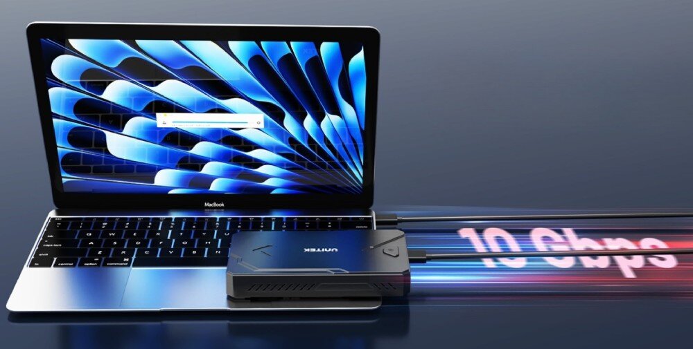 Obudowa dysku UNITEK S1229CBK01 Czarna obudowa dysku leżąca na srebrnym laptopie, połączona z nim kablem. Z boku urządzenia wychodzą smugi światła z napisem '10 Gbps', co symbolizuje prędkość przesyłu danych
