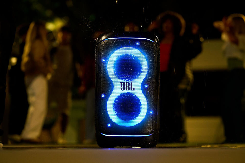 Power audio JBL PartyBox 520 - Nie boi się zachlapania, IPX4, Power audio oblany wodą, w tle osoby bawiące się w rytm muzyki
