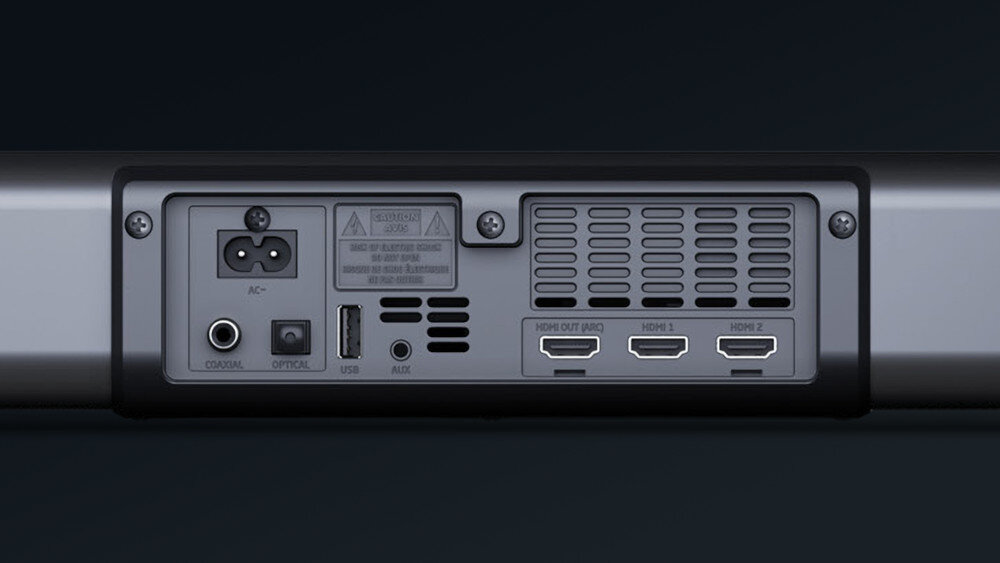 Tył soundbara z widocznymi portami: zasilanie AC, COAXIAL, OPTICAL, USB, AUX oraz trzy porty HDMI oznaczone jako HDMI OUT (ARC), HDMI 1 i HDMI 2. Obok portów znajduje się kratka wentylacyjna.